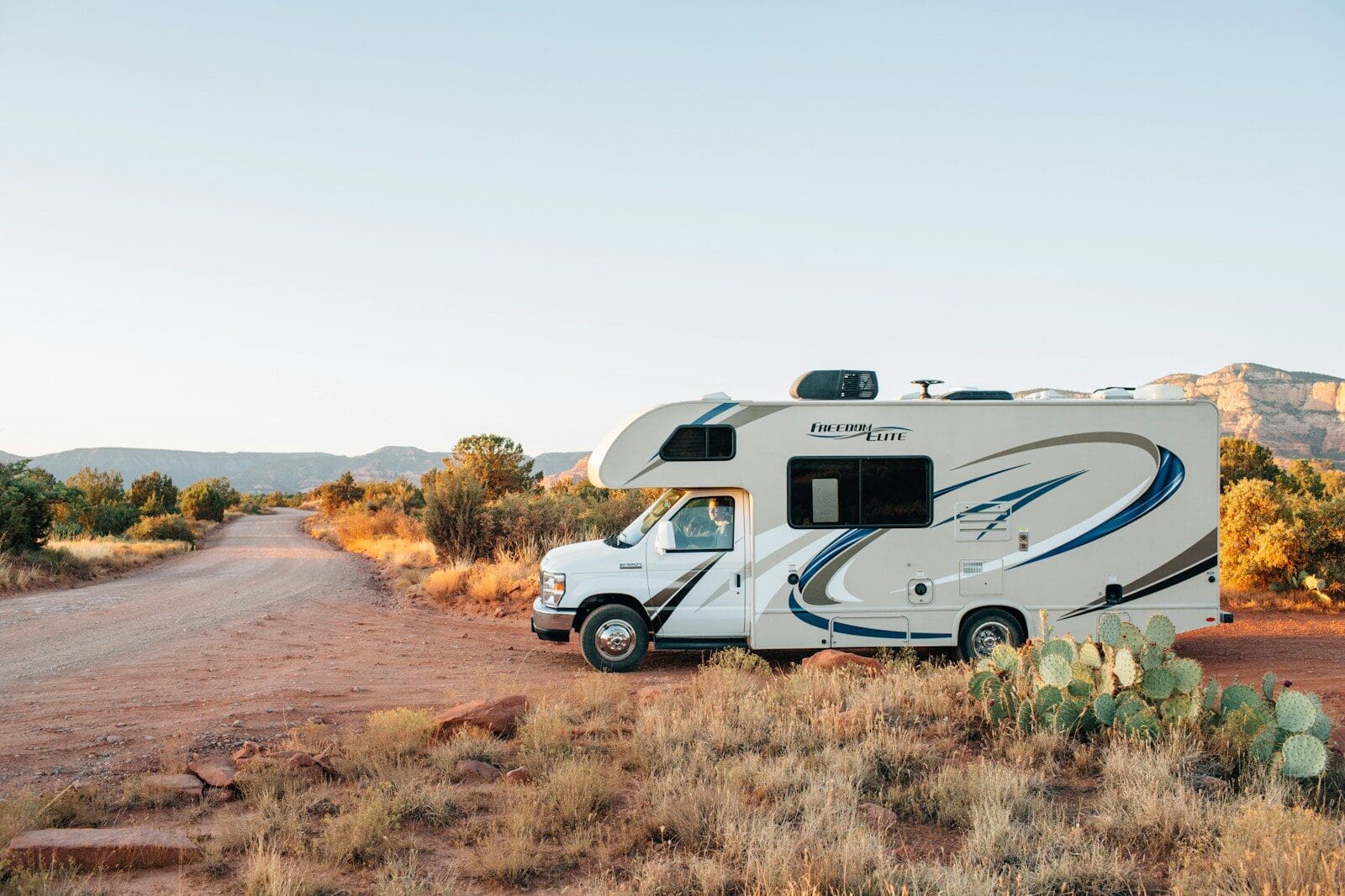white and brown rv on brown grass field during daytime